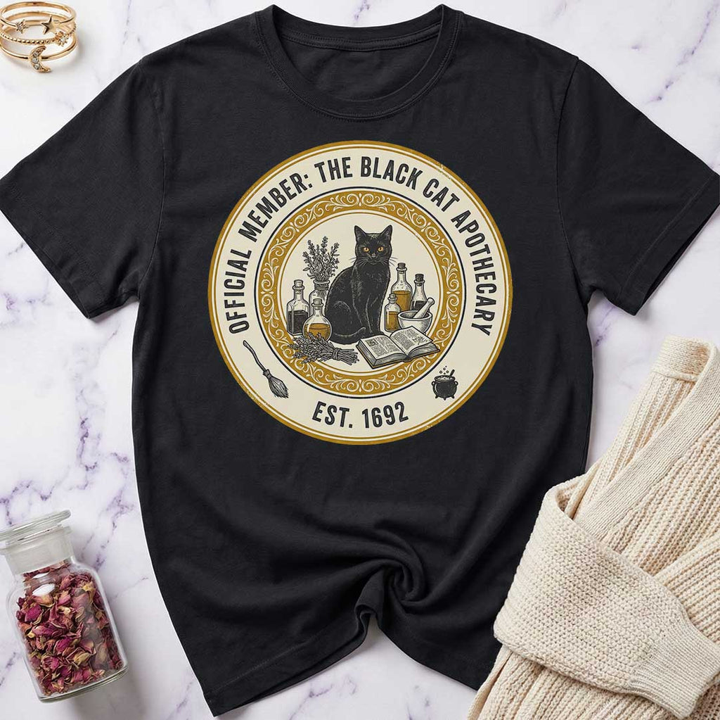 Black t-shirt with a black cat and apothecary design on a marble surface.