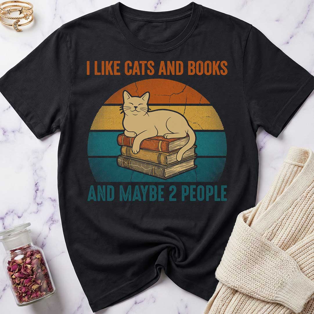 Black t-shirt with a cat and books graphic and text on a marble surface.