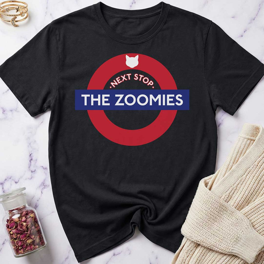 Black t-shirt with 'Next Stop, The Zoomies' graphic design on a marble surface.