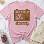 Pink t-shirt with 'World's Best Cat Mom Exit Now' design on a marble surface.