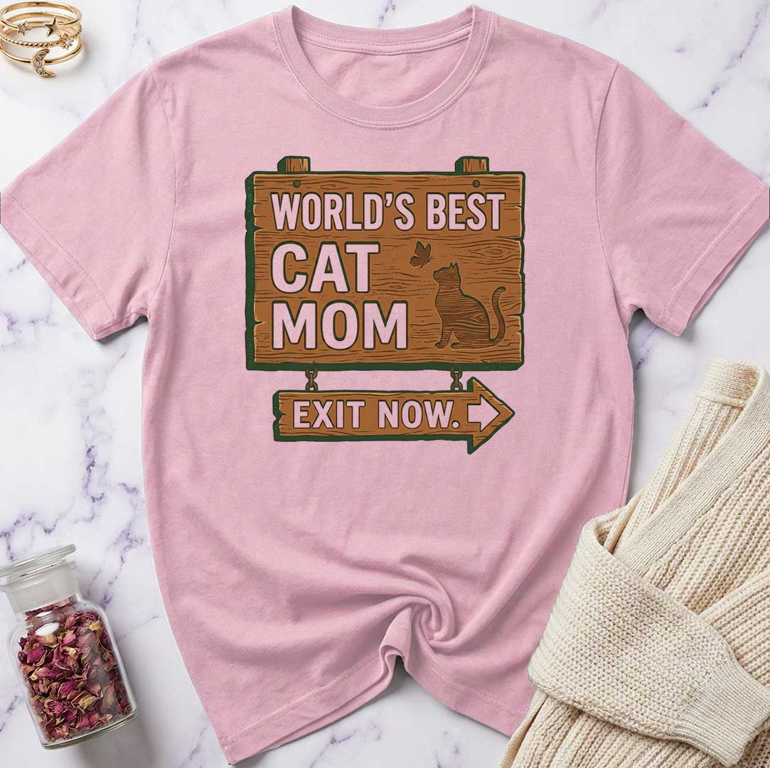 Pink t-shirt with 'World's Best Cat Mom Exit Now' design on a marble surface.