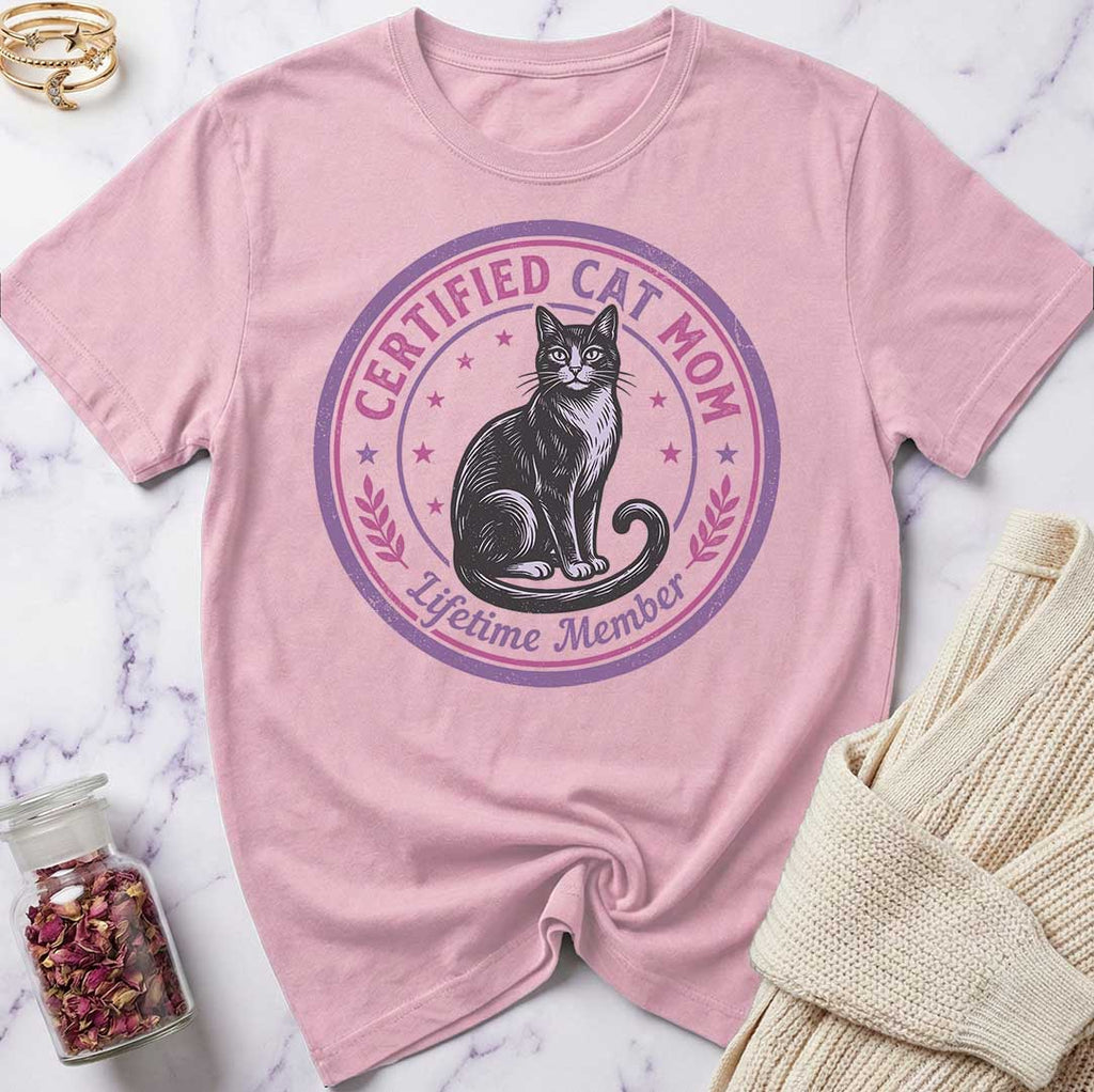 Pink t-shirt with a cat graphic and text on a marble surface