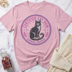 Pink t-shirt with a cat graphic and text on a marble surface