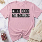 Pink t-shirt with 'Next Stop The Zoomies' text on a marble surface.