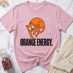 Pink t-shirt with orange cat graphic and 'Orange Energy' text on a marble surface.