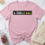 Pink t-shirt with a humorous street sign design on a marble surface.