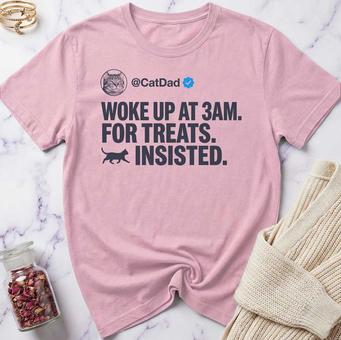 Pink t-shirt with humorous text design on a marble surface.