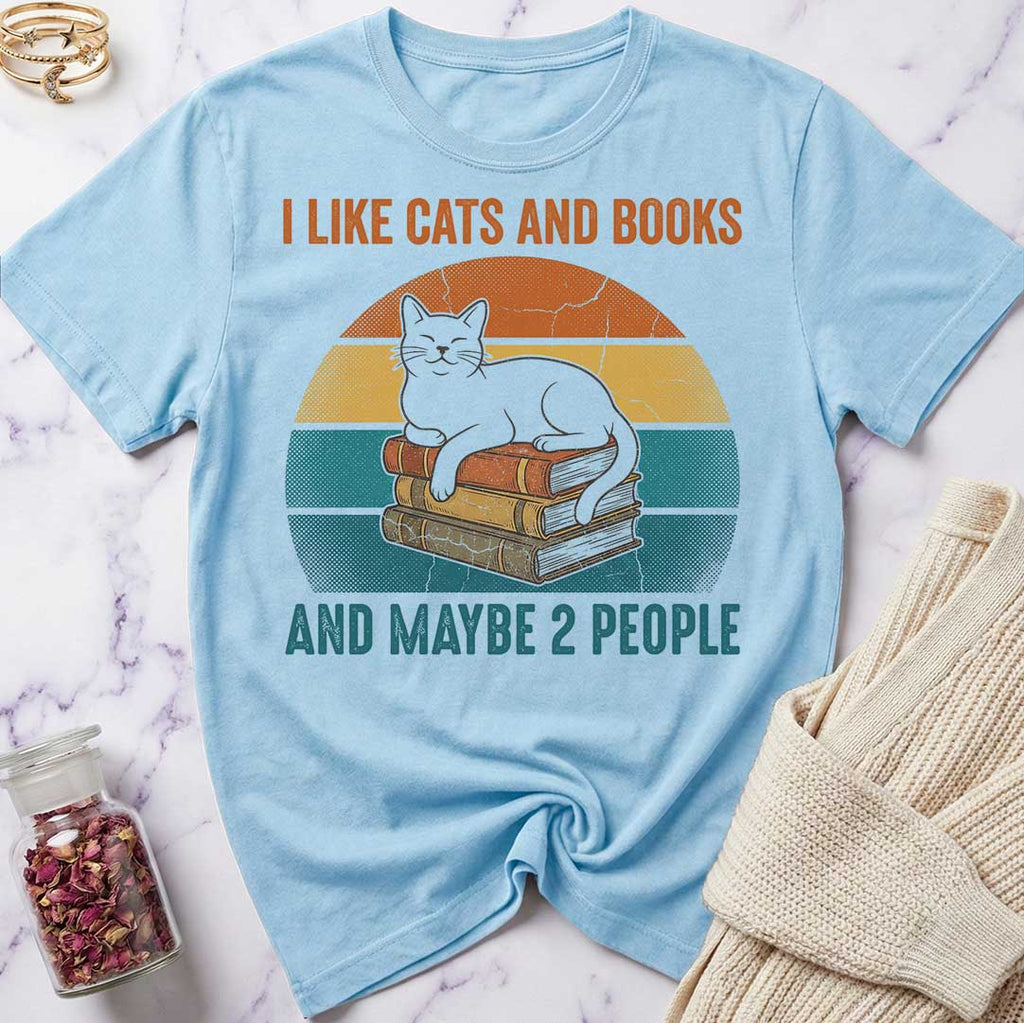Light blue t-shirt with a cat and books graphic and text on a marble surface.