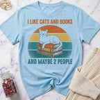 Light blue t-shirt with a cat and books graphic and text on a marble surface.