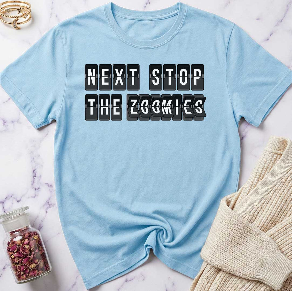 Light blue t-shirt with 'Next Stop The Zoomies' text on a marble surface.