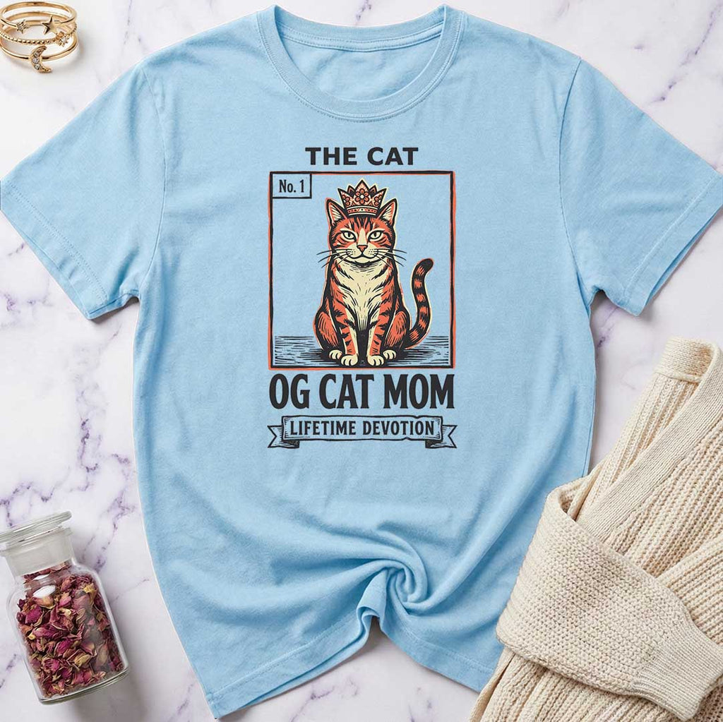 Light blue t-shirt with a cat graphic and text on a marble surface.