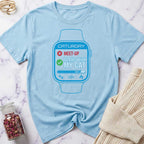 Light blue t-shirt with a graphic of a smartwatch and text on a marble surface.