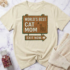 Beige t-shirt with 'World's Best Cat Mom Exit Now' graphic on a marble surface.