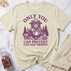 Beige t-shirt with purple graphic of a cat in a hat and text on a marble surface.