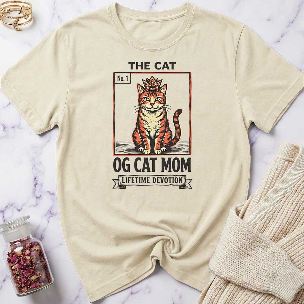Beige t-shirt with cat graphic and text on a marble surface