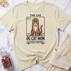 Beige t-shirt with cat graphic and text on a marble surface