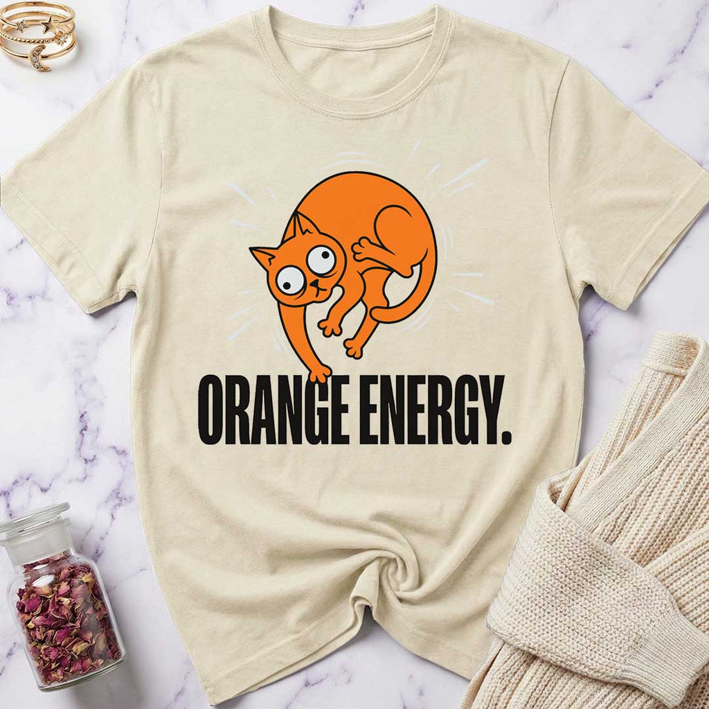 Beige t-shirt with an orange cat graphic and 'Orange Energy' text on a marble surface.