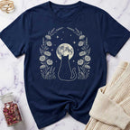 Navy blue t-shirt with a cat and moon design on a marble surface.