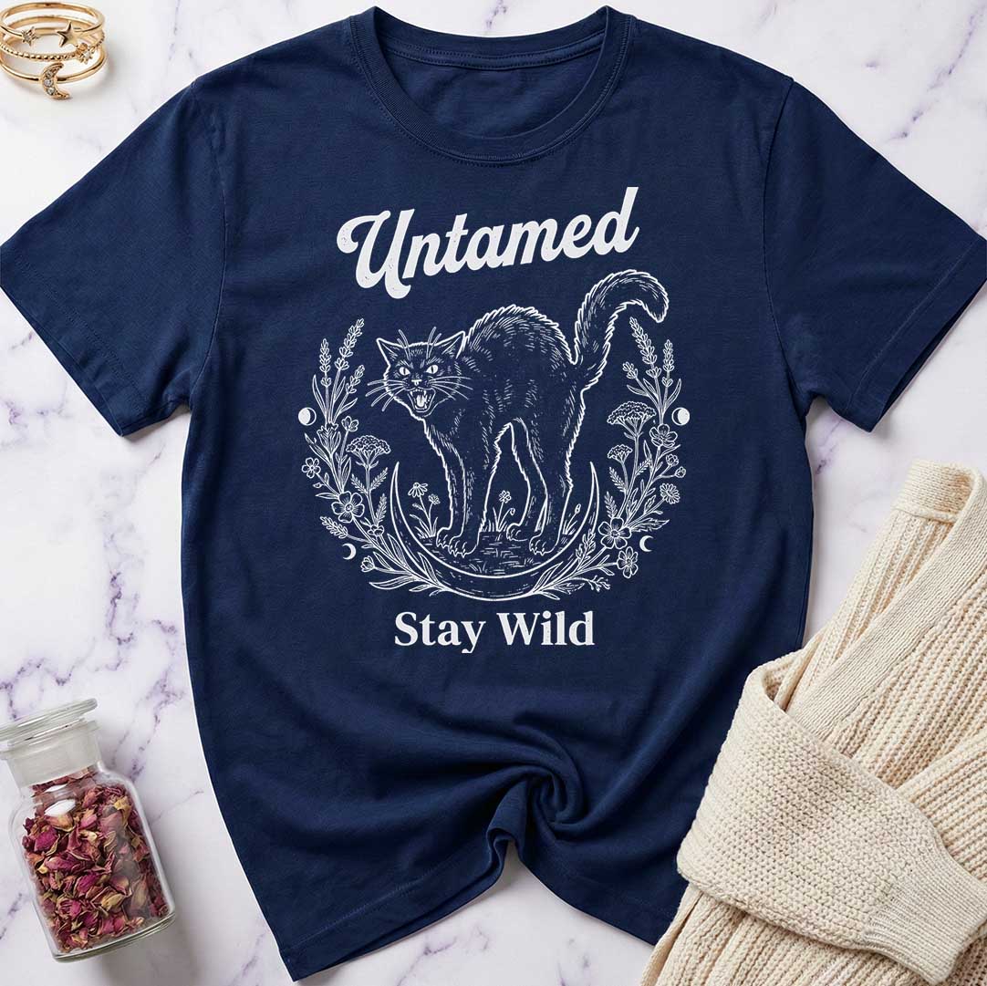 Navy blue t-shirt with white cat graphic and text 'Untamed Stay Wild' on a marble surface.