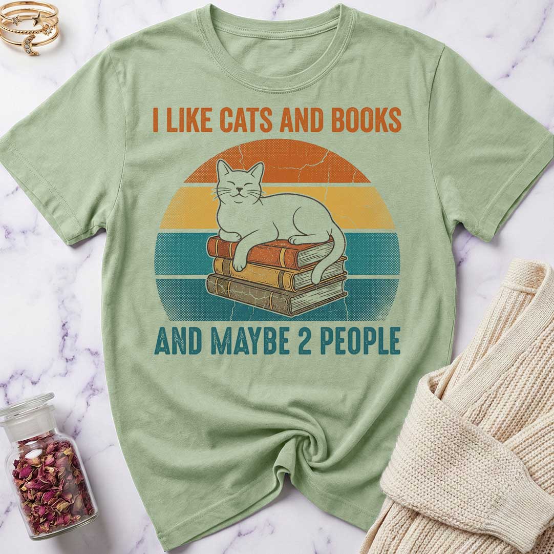 Green t-shirt with a cat and books graphic and text on a marble surface.