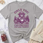 Gray t-shirt with purple graphic of a cat in a hat and text on a marble surface.