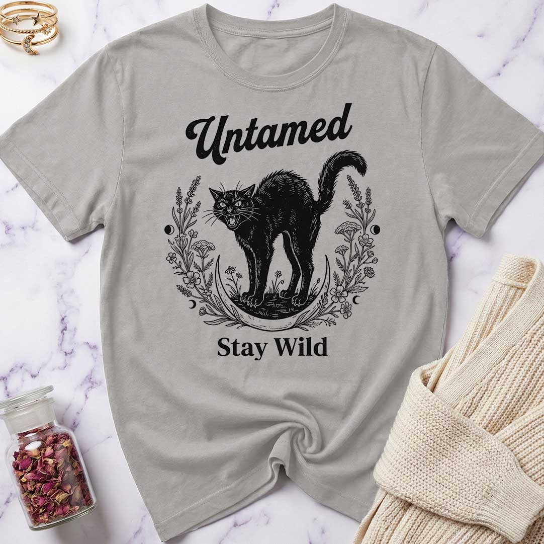 Gray t-shirt with black cat graphic and text 'Untamed Stay Wild' on a marble surface.