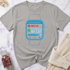 Gray t-shirt with a graphic of a smartwatch and text on a marble surface.