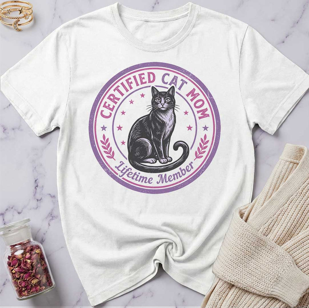 White t-shirt with a cat graphic and text on a marble surface