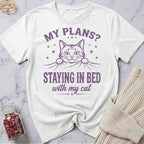 White t-shirt with purple cat graphic and text on a marble surface