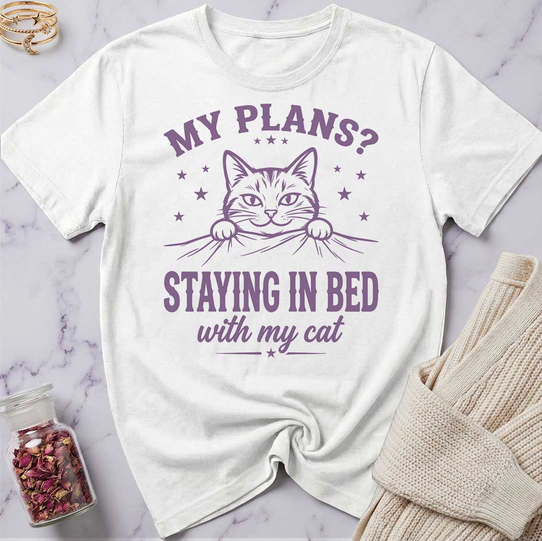 White t-shirt with purple cat graphic and text on a marble surface