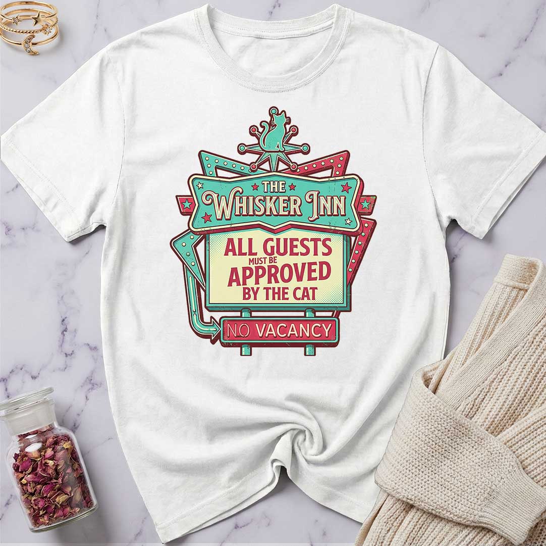 White t-shirt with 'The Whisker Inn' graphic design on a marble surface.