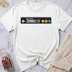 White t-shirt with a graphic design on a marble surface with a sweater and jar of rose petals.