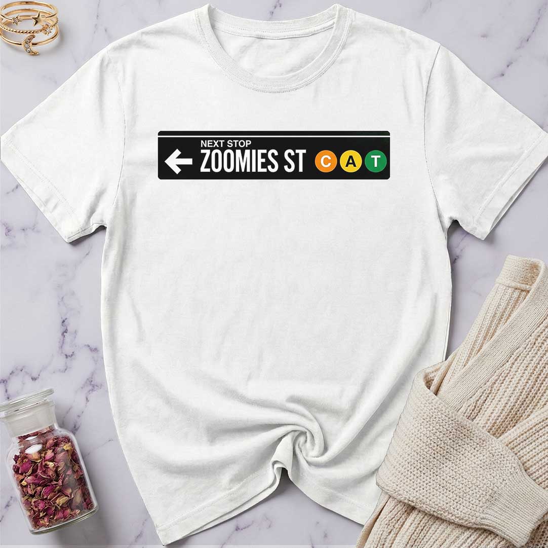 White t-shirt with a graphic design on a marble surface with a sweater and jar of rose petals.