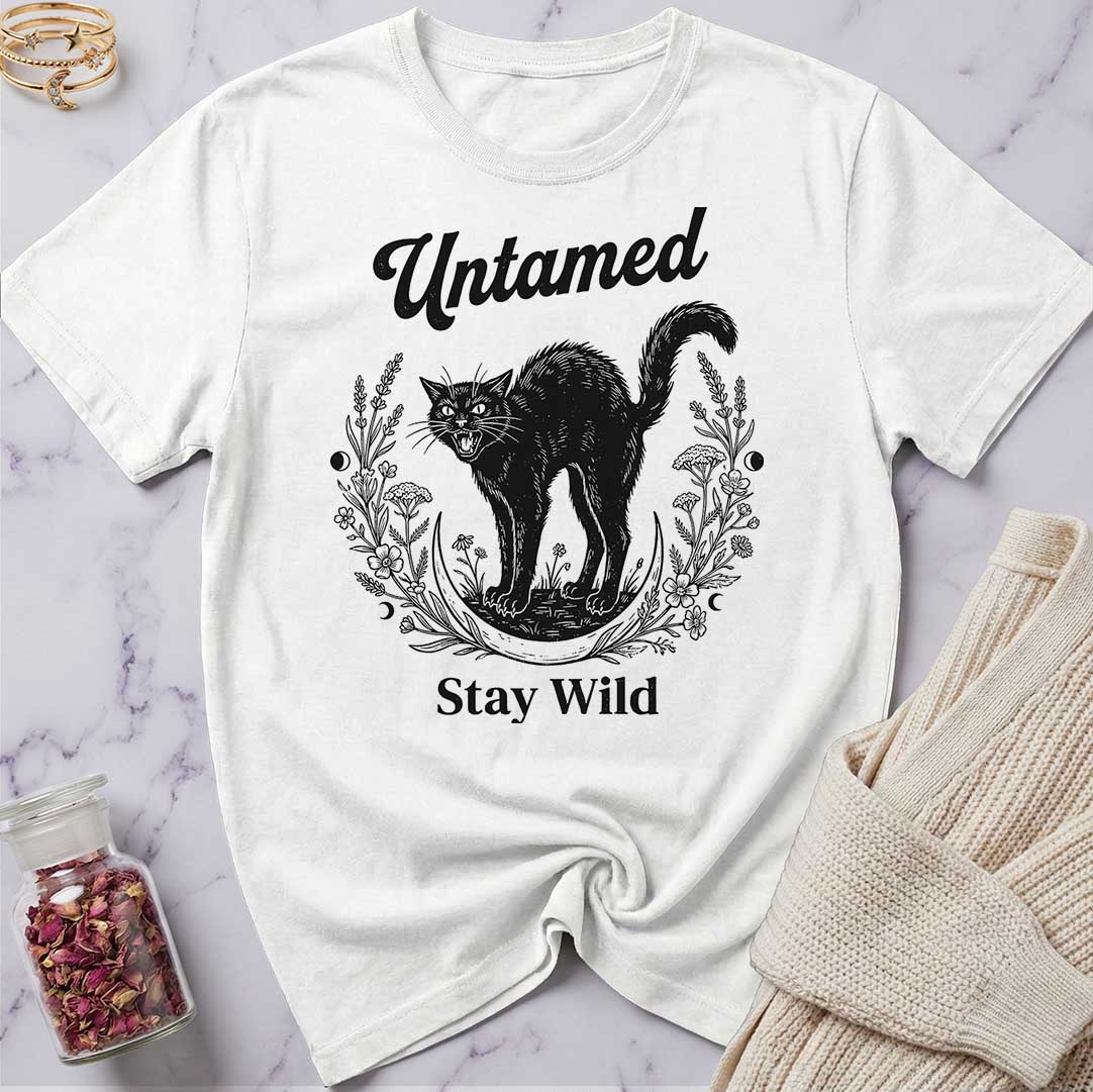 White t-shirt with black cat graphic and text 'Untamed Stay Wild' on a marble surface.